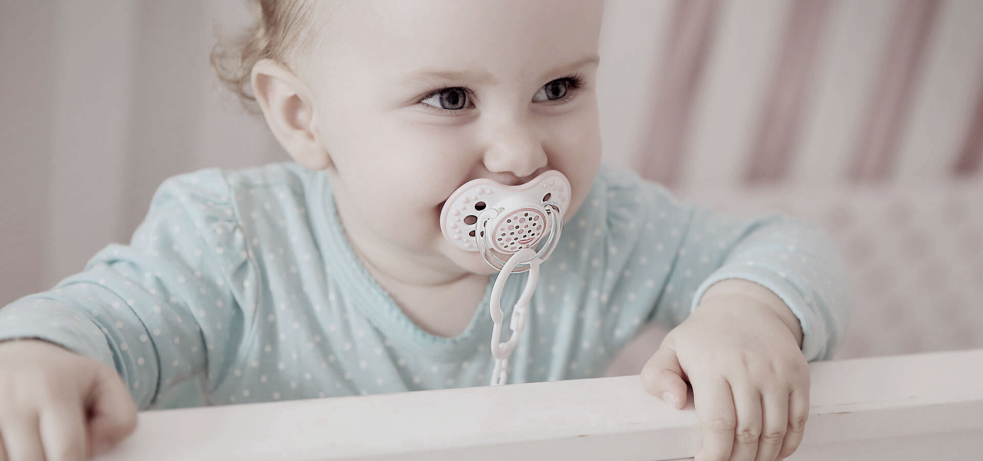 A little baby standing and smiling in a crib