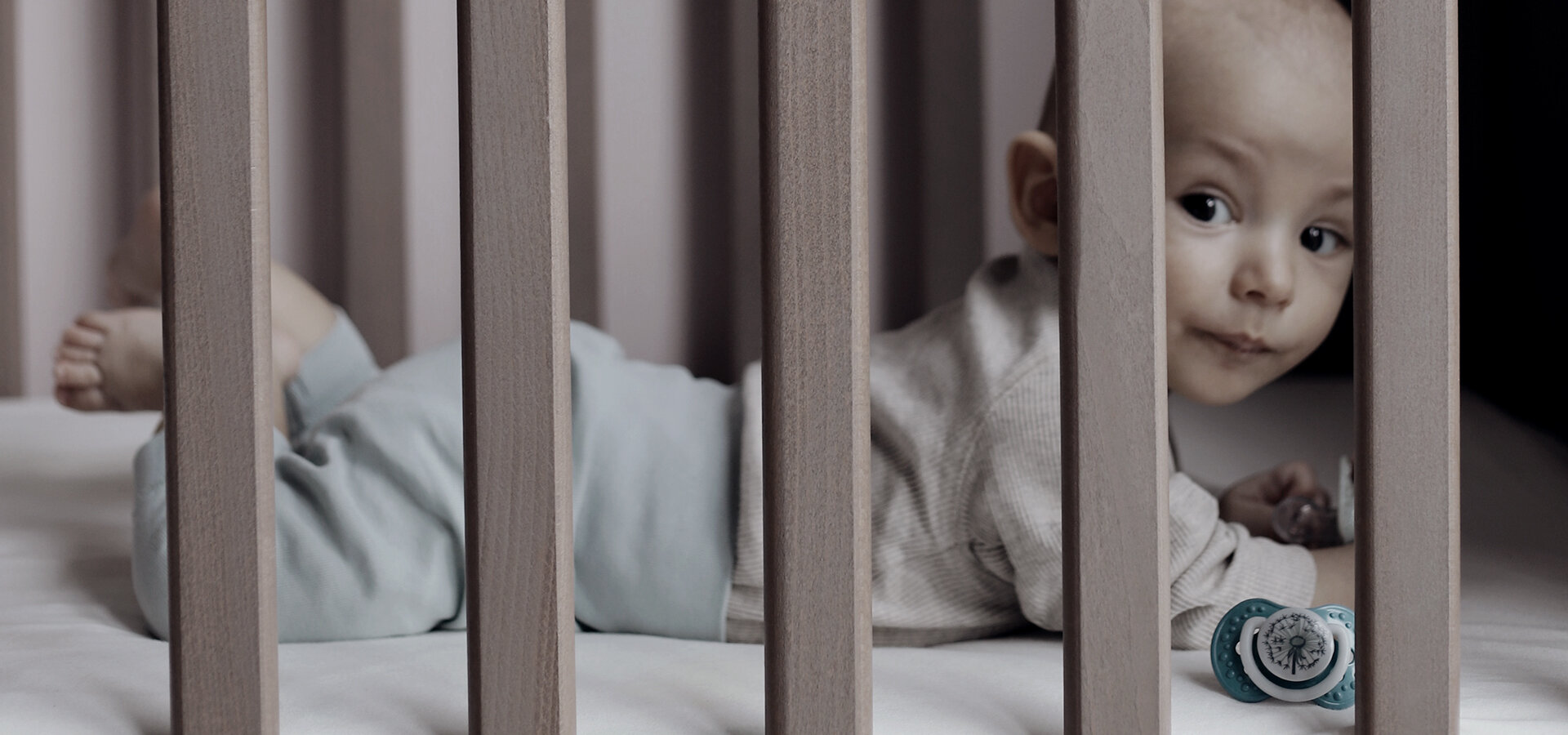 Маленький мальчик лежит в детской кроватке